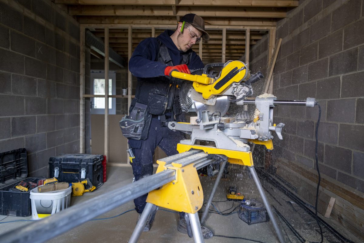 Carpenter cutting timber with a mitre saw on site