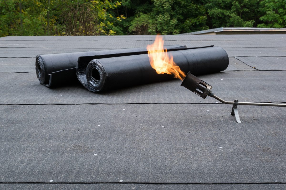 Roofer torching down felt on a flat roof
